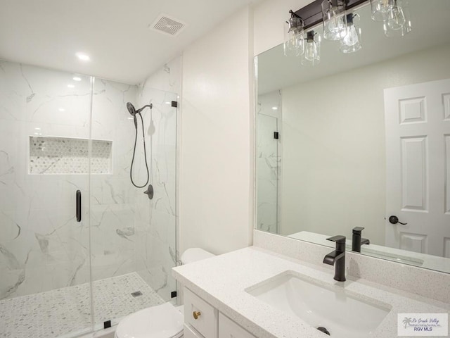 bathroom with vanity, a shower with door, and toilet