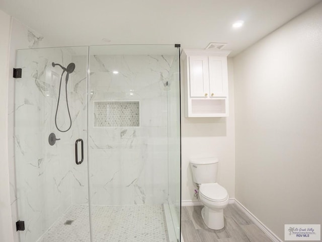 bathroom featuring hardwood / wood-style flooring, a shower with shower door, and toilet