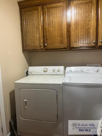 laundry area with washing machine and clothes dryer and cabinets