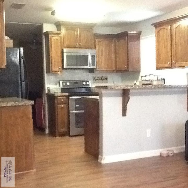 kitchen featuring stainless steel appliances, light hardwood / wood-style flooring, and a breakfast bar area