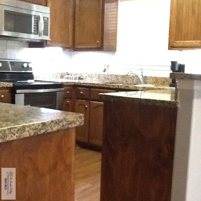 kitchen featuring electric range, light wood-type flooring, and sink
