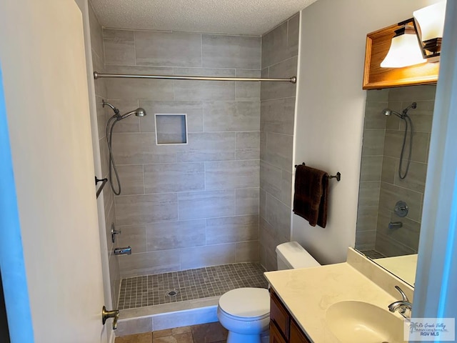 bathroom with toilet, tiled shower, and vanity