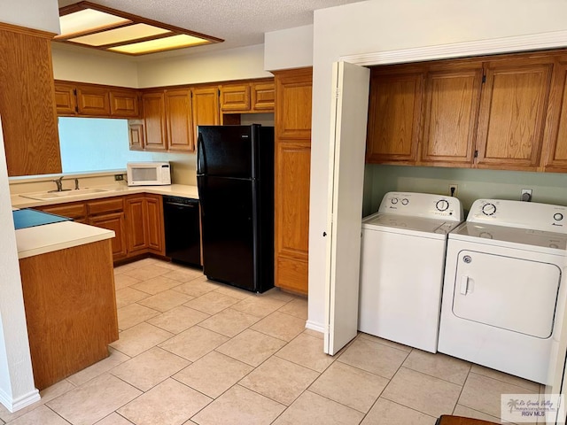 kitchen with brown cabinets, a sink, independent washer and dryer, and black appliances