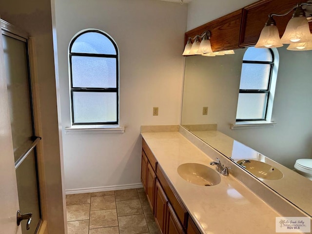 full bath featuring toilet, a shower with shower door, vanity, baseboards, and tile patterned floors