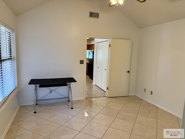 empty room featuring light tile patterned floors, baseboards, visible vents, and high vaulted ceiling