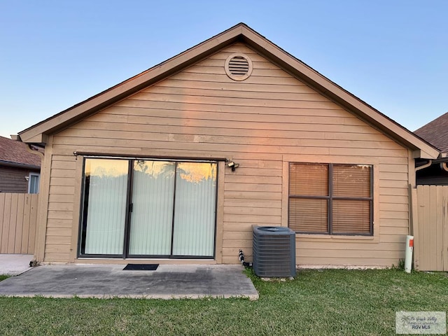 back of house with fence, central AC unit, and a yard