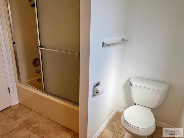 bathroom featuring bath / shower combo with glass door, tile patterned flooring, toilet, and baseboards