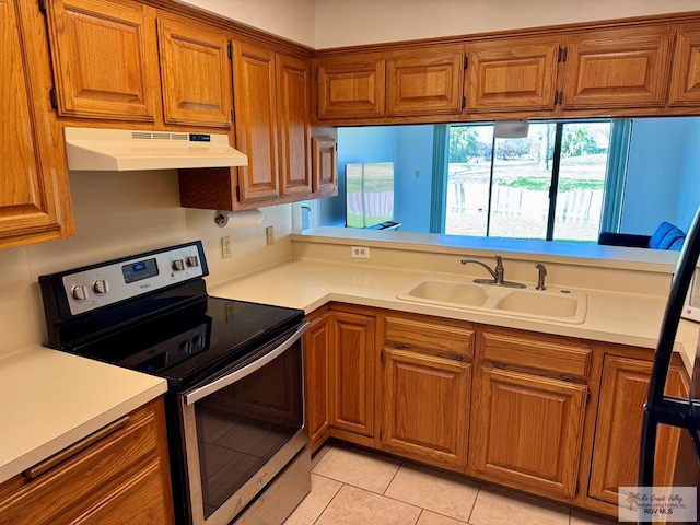 kitchen with light countertops, brown cabinetry, stainless steel range with electric cooktop, a sink, and under cabinet range hood