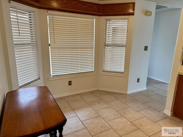 unfurnished dining area featuring light tile patterned floors, visible vents, and baseboards