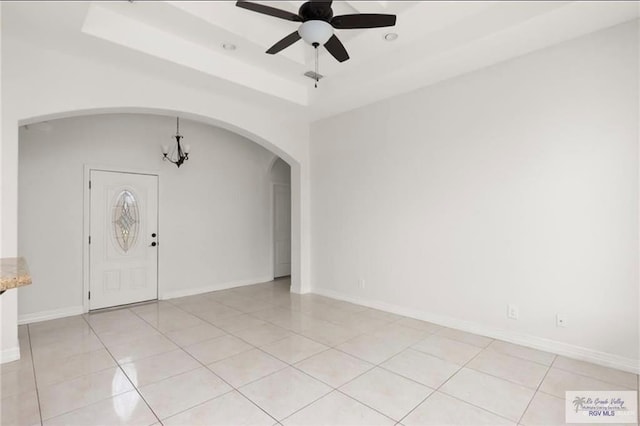 foyer featuring ceiling fan with notable chandelier, a tray ceiling, and light tile patterned flooring