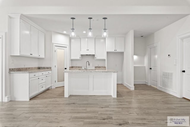 1838 Castillo St, Olmito, TX 78575 - kitchen with recessed lighting, white cabinetry, light wood-style floors, hanging light fixtures, and a kitchen island with sink