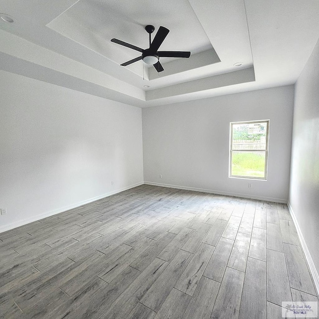 empty room featuring hardwood / wood-style floors, a tray ceiling, and ceiling fan