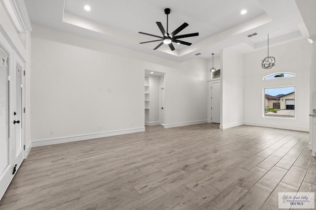 1838 Castillo St, Olmito, TX 78575 - unfurnished living room featuring a tray ceiling, a ceiling fan, light wood-type flooring, recessed lighting, and a chandelier