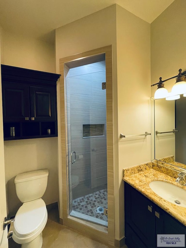 bathroom featuring vanity, a shower stall, and toilet