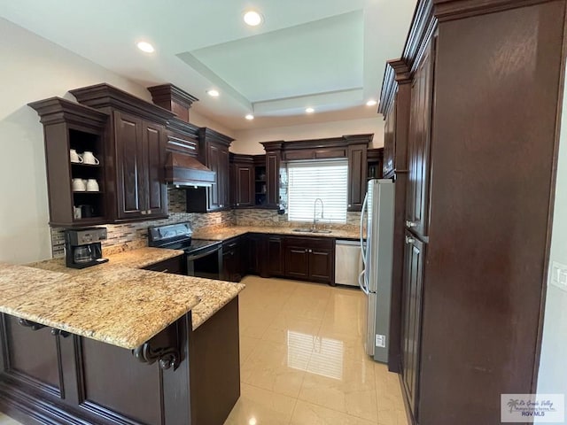 kitchen with dark brown cabinets, range hood, a peninsula, stainless steel appliances, and a raised ceiling