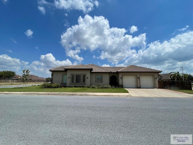 mediterranean / spanish home featuring fence, a tile roof, concrete driveway, stucco siding, and a garage