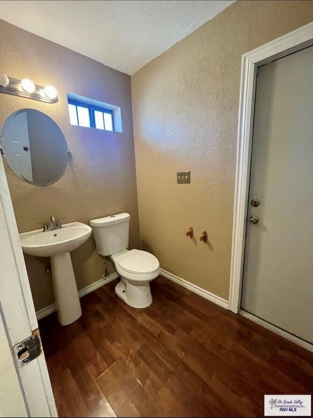 bathroom with hardwood / wood-style floors, a textured ceiling, toilet, and sink