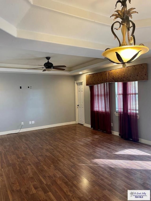 unfurnished room featuring dark hardwood / wood-style flooring, a raised ceiling, and ceiling fan