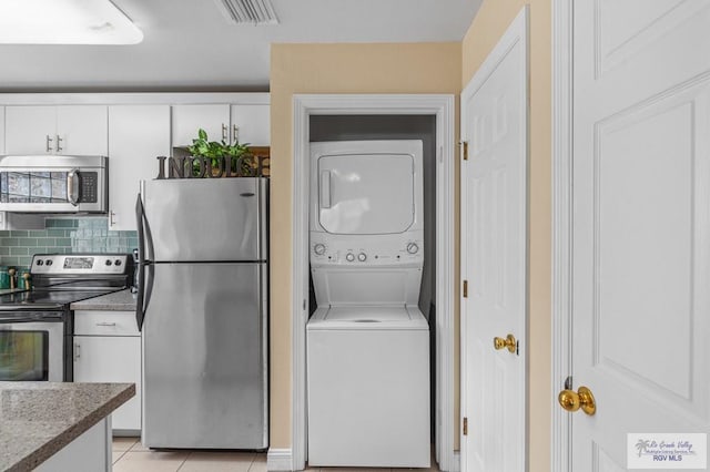 106 Atol St Unit 7, South Padre Island, TX 78597 - laundry room featuring stacked washing machine and dryer and light tile patterned floors