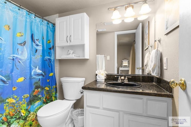 bathroom with a shower with curtain, vanity, toilet, and a textured ceiling