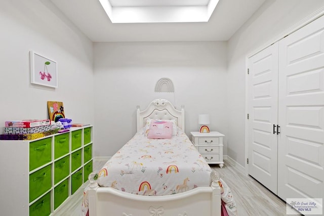 bedroom with light hardwood / wood-style flooring, a closet, and a skylight