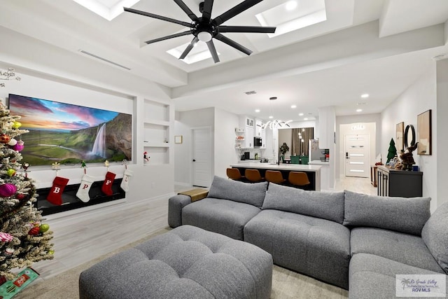 living room featuring built in features, light wood-type flooring, and ceiling fan