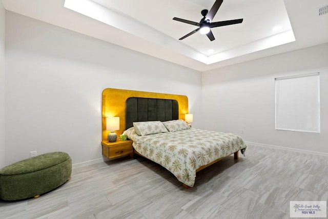 bedroom featuring ceiling fan and a tray ceiling