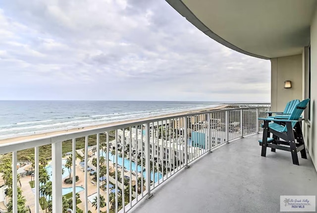 balcony with a water view and a view of the beach