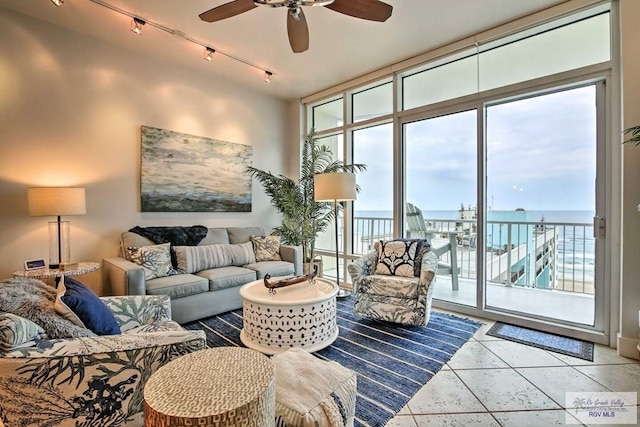 tiled living room featuring a water view, a wall of windows, and ceiling fan