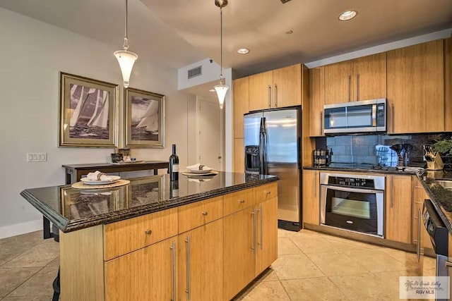 kitchen with pendant lighting, appliances with stainless steel finishes, an island with sink, a kitchen breakfast bar, and backsplash