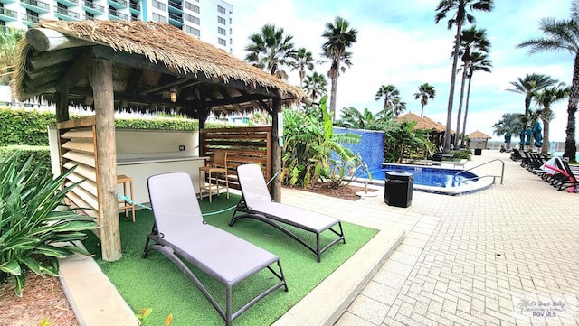 view of patio / terrace featuring a community pool, exterior bar, and a gazebo