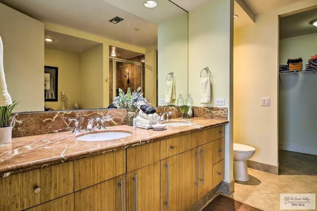 bathroom featuring a shower with shower door, toilet, vanity, and tile patterned flooring