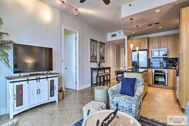 kitchen featuring ceiling fan, appliances with stainless steel finishes, tasteful backsplash, decorative light fixtures, and a kitchen island with sink