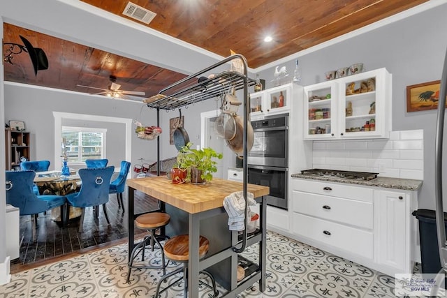 kitchen featuring appliances with stainless steel finishes, wood ceiling, light hardwood / wood-style flooring, dark stone countertops, and white cabinets