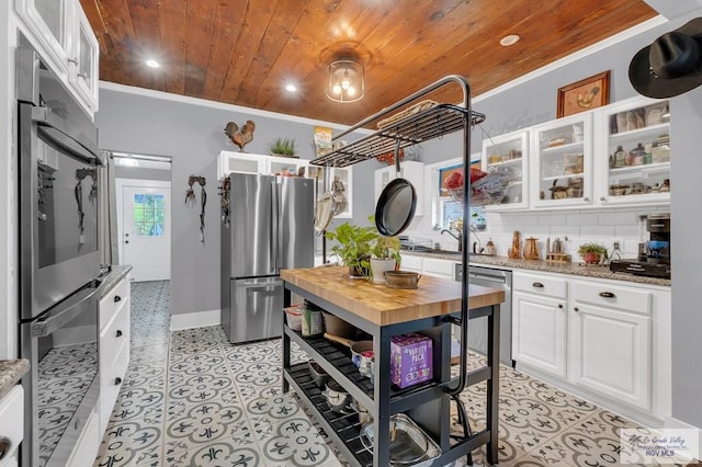 kitchen featuring white cabinetry, light stone countertops, stainless steel appliances, backsplash, and wood ceiling