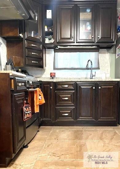 kitchen featuring sink, decorative backsplash, dark brown cabinets, light stone counters, and extractor fan