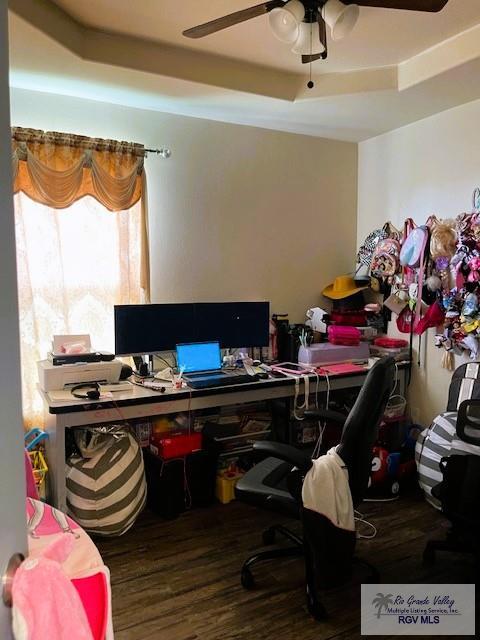 home office featuring a raised ceiling, ceiling fan, and hardwood / wood-style floors