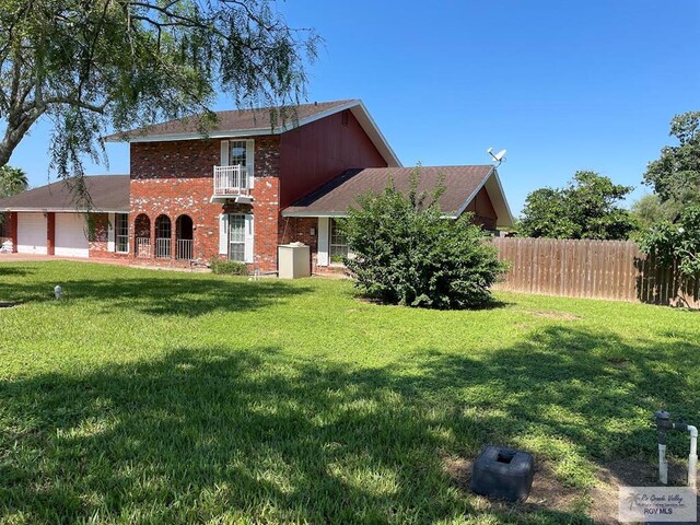 view of front facade with a balcony, a garage, and a front lawn