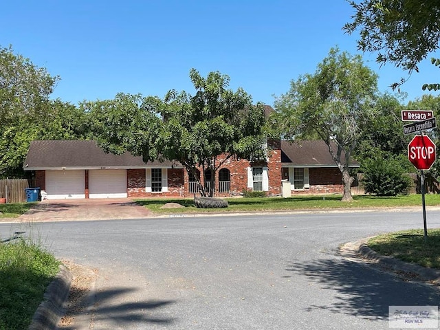 200 E Resaca Dr, Los Fresnos, TX 78566 - view of property hidden behind natural elements featuring a garage, brick siding, and driveway