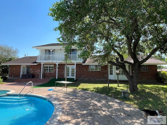 back of house featuring a patio area, a balcony, and french doors