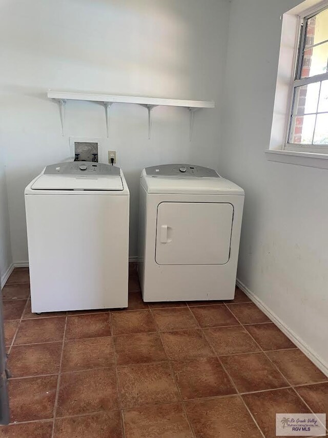 clothes washing area featuring dark tile patterned flooring and washing machine and clothes dryer