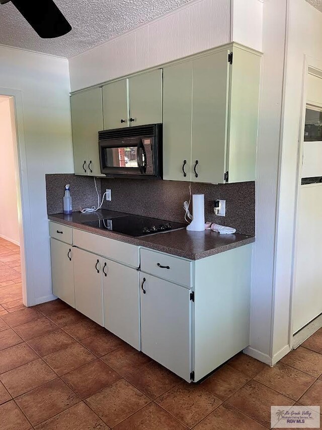 kitchen with white cabinets, tasteful backsplash, a textured ceiling, green cabinetry, and black appliances