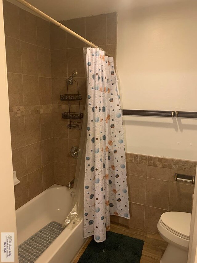 bathroom featuring tile walls, toilet, and shower / bathtub combination with curtain