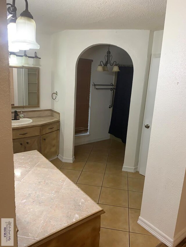 bathroom with a textured ceiling, tile patterned flooring, and vanity