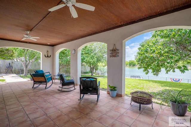 view of patio / terrace featuring ceiling fan, a water view, and a fire pit