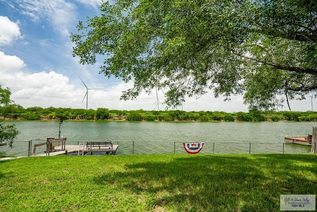 view of dock with a lawn and a water view