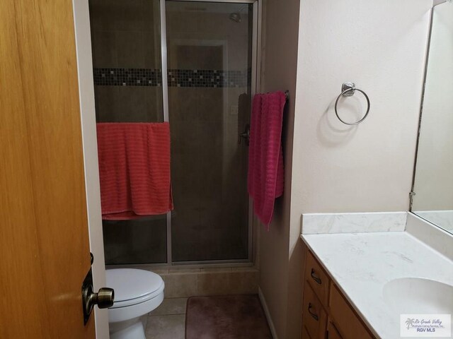 bathroom featuring toilet, vanity, tile patterned floors, and an enclosed shower