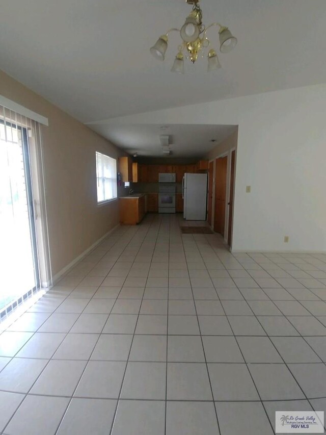 unfurnished living room with a chandelier, light tile patterned floors, and a wealth of natural light