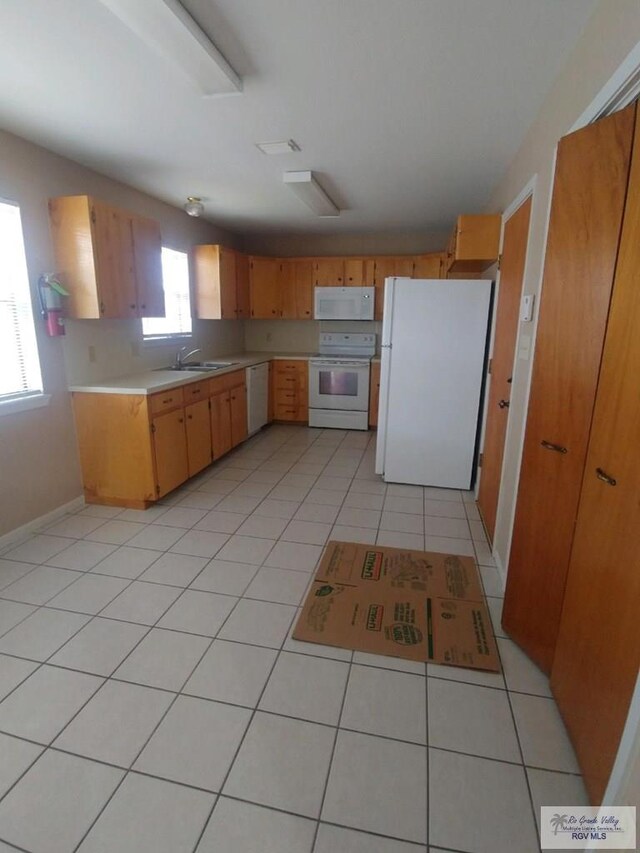 kitchen featuring sink, white appliances, and light tile patterned flooring