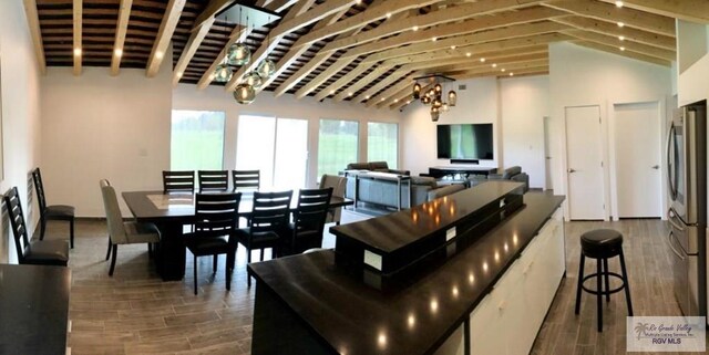 dining area with a notable chandelier, vaulted ceiling, and hardwood / wood-style flooring